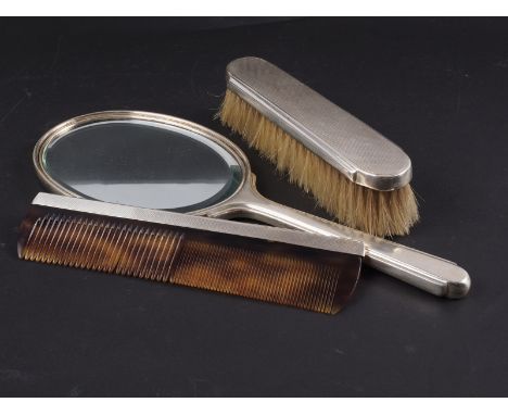 An engine turned silver backed toilet mirror, and a companion brush and comb 