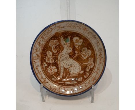 An Islamic glazed ceramic lustre plate decorated with a hare among flowers within a calligraphic border.  H.15.5cm 