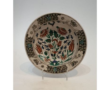 An 17th or 18th century Turkish Iznik hand painted glazed ceramic plate, decorated with a stylised floral design within a scr