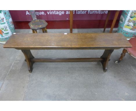 An oak bench with carved guitar motif to the bottom rail