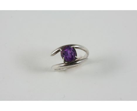 A PURPLE SAPPHIRE SINGLE STONE RING set with an oval-shaped purple sapphire. Size L.