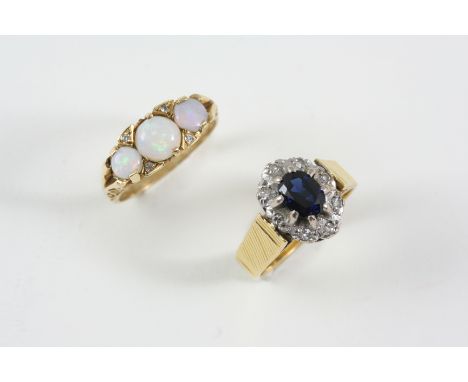 A SAPPHIRE AND DIAMOND CLUSTER RING the oval-shaped sapphire is set within a surround of small diamonds, in 18ct. gold, size 