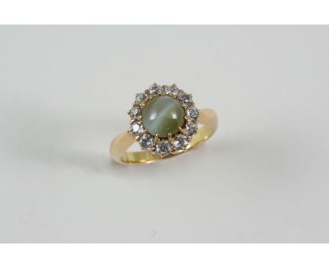 A CHRYSOBERYL CAT'S-EYE AND DIAMOND CLUSTER RING the circular-cut chrysoberyl is set within a surround of eleven old brillian