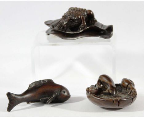 THREE JAPANESE WOOD NETSUKE, carved as a toad on a leaf, a fish and a frog and snail on a mushroom, all signed (3)