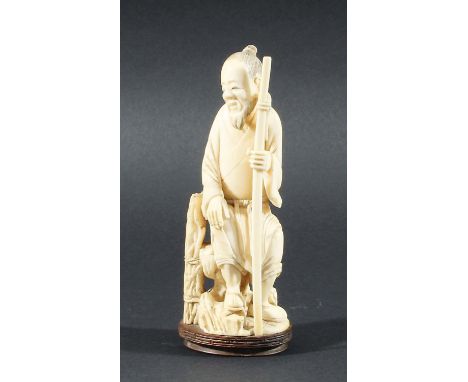 JAPANESE IVORY OKIMONO, late 19th century, carved as a man seated holding a staff, height excluding wooden base 16.5cm