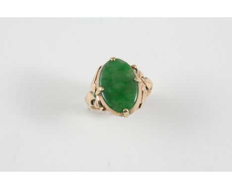 A JADE AND GOLD RING the oval section of jade is set within a gold foliate engraved mount. Size J.