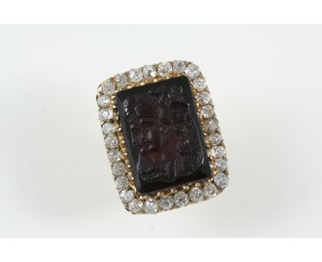 A CARVED BLACK ONYX CAMEO RING set with a rectangular black onyx cameo, possibly depicting Medusa/The Gorgons, within a surro