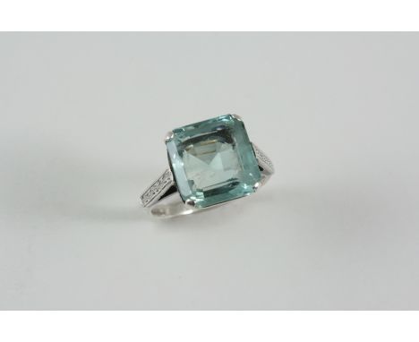 AN AQUAMARINE SINGLE STONE RING set with a square-shaped aquamarine with engraved shoulders. Size N.