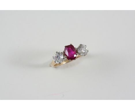 A RUBY AND DIAMOND THREE STONE RING the cushion-shaped ruby is set with two circular-cut diamonds, in gold. Accompanied by re