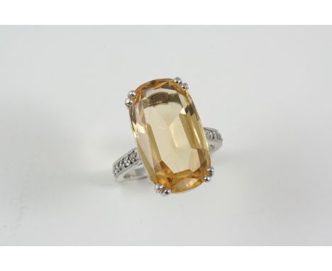 A TOPAZ AND DIAMOND RING the oval-shaped topaz is set with nine circular diamonds to each shoulder. Size O.