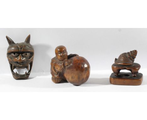 THREE JAPANESE BOXWOOD NETSUKE, of a oni mask (signed), a snail on a table and boy with a sack or ball (3)