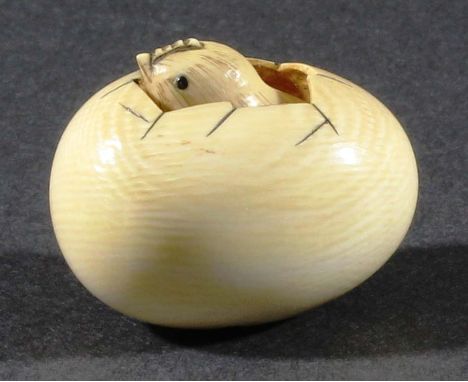 JAPANESE IVORY NETSUKE, carved as a chick hatching from an egg, red and black signatures, length 4cm