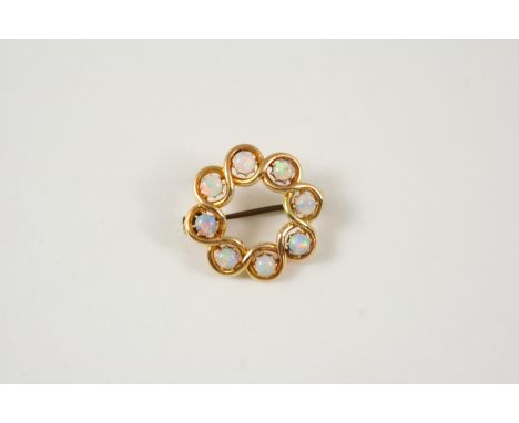 AN OPAL AND GOLD BROOCH the flowerhead design is set with circular opal cabochons, 3cm. dia. With metal pin.