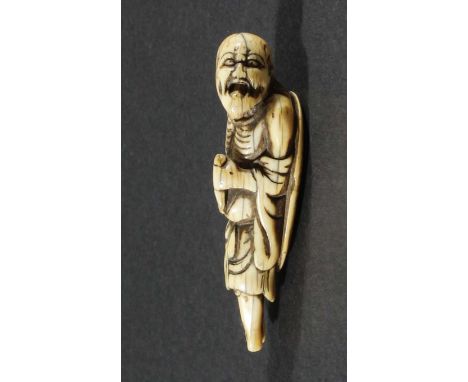 JAPANESE IVORY NETSUKE, 18th century, carved as a beggar with a hat on his back, height 7cm