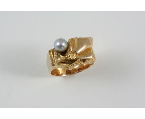 A FINNISH CULTURED PEARL AND GOLD RING the abstract textured design is set with a grey cultured pearl, the shank is open to o