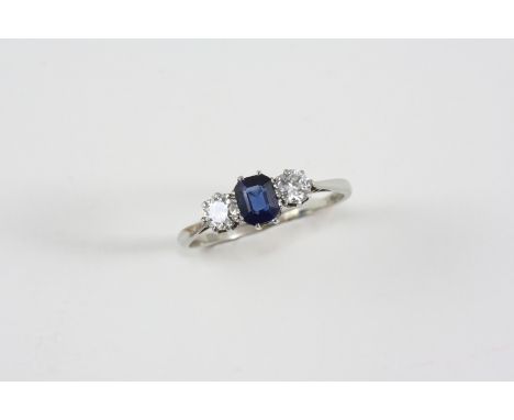 A SAPPHIRE AND DIAMOND THREE STONE RING the octagonal-shaped sapphire is set with two circular-cut diamonds, in 18ct. white g