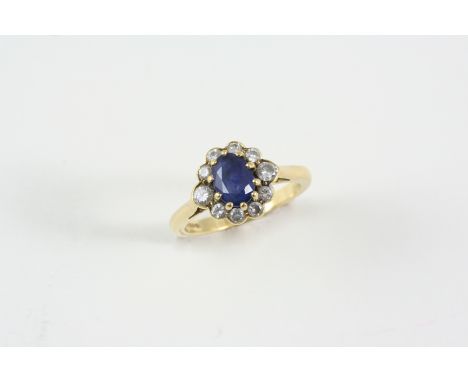 A SAPPHIRE AND DIAMOND CLUSTER RING the oval-shaped sapphire is set within a surround of two circular-cut diamonds and eight 