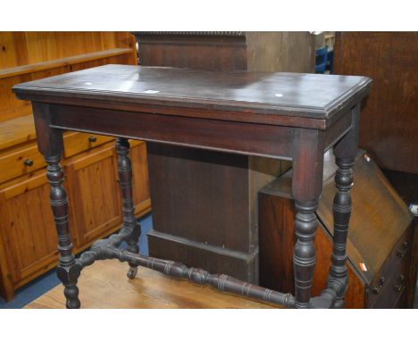AN EDWARDIAN MAHOGANY FOLD OVER CARD TABLE with turned legs and H stretcher and a green baize inner, width 83cm x depth 40cm 
