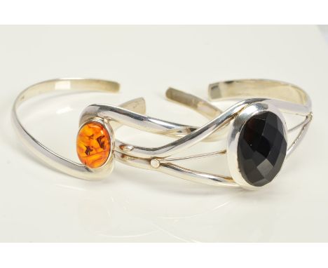 TWO TORQUE BANGLES, the first of crossover design set with a central oval modified amber cabochon, the second set with a cent