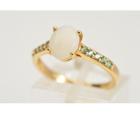 A 9CT GOLD GEM RING, designed as a central oval jelly opal cabochon flanked by a row of five circular green gems to the shoul