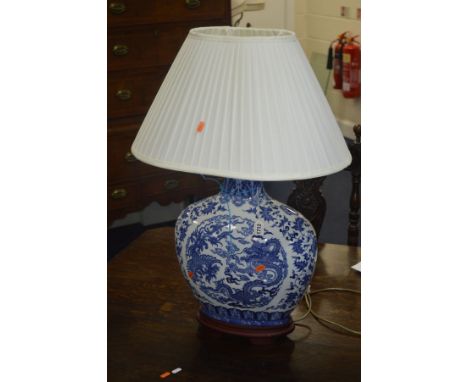 A MODERN CHINESE STYLE PORCELAIN TABLE LAMP of flattened baluster form, decorated with dragons and foliage, with wooden mount