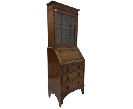 Early 20th century oak bureau bookcase, the projecting cornice over carved frieze and lead glazed doors, leading into bureau 