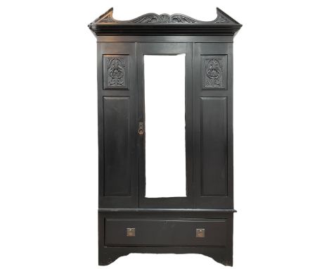 19th century black painted wardrobe, the pointed and scroll carved pediment over panelled and carved front with central bevel