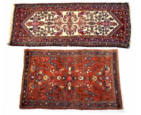 An Iranian wool rug with floral motifs on a red ground within stepped multi-borders in blue, pink, cream, brown and black col