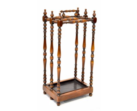 A reproduction stained wood stick stand with turned supports and carrying handle, drip tray to rectangular base and on turned