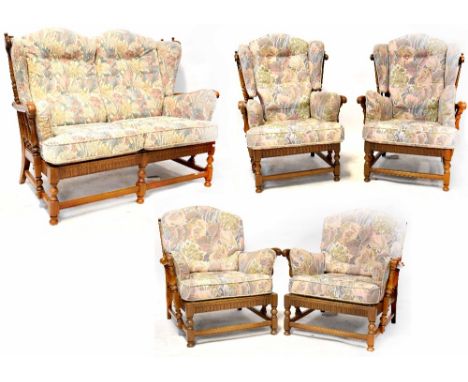 An Ercol oak Colonial-style five-piece cottage suite, design no.9322, comprising two-piece sofa, two low-back armchairs and t