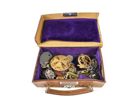 A small jewellery case in the form of a brown leather suitcase containing a small quantity of military-related items to inclu