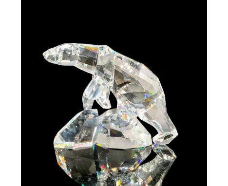 A clear shining crystal figure of a polar bear with many smooth cuts atop of two glaciers. Artist signature. Swarovski backst