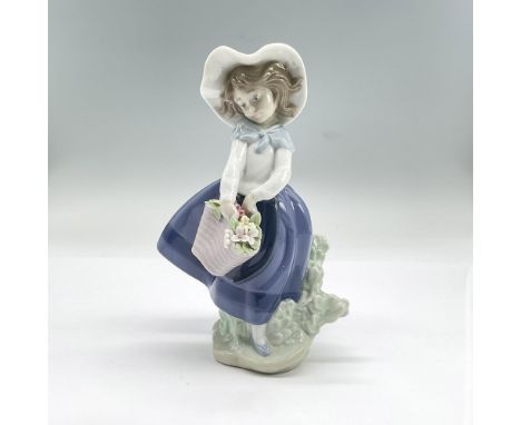 Glazed porcelain figure of a young girl in a wide brimmed hat, blue skirt and white top holding a basket of flowers. Lladro b