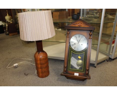 A TURNED WOODEN TABLE LAMP TOGETHER WITH A REPRODUCTION LEGEND WALL CLOCK, LAMP HEIGHT WITH SHADE 68 CM