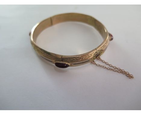 A yellow metal hollow hinged bangle - black and white enamelled centre sections interspaced with four oval cabochon cut amber