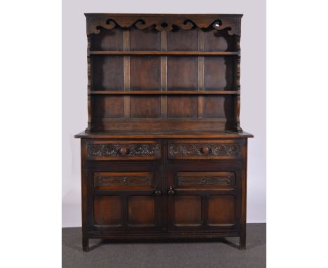 Oak and stained wood dresser, with a two shelf delft rack, base fitted with two carved drawers over two panelled doors, width