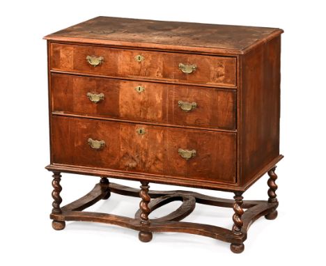 An antique walnut veneered chest of drawers, with parquetry top above three drawers with brass drop handles with shaped backp