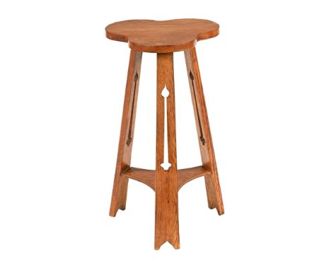 An Arts & Crafts oak occasional table of shaped outline, with angled pierced supports and low shelf.  Height 67 cm, maximum w