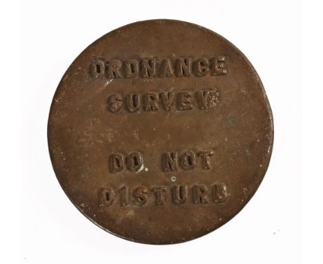 A brass plaque marked Ordnance Survey Do Not disturb.  diameter 15 cm.