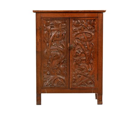 A Victorian oak Arts & Crafts cupboard, with a pair of carved doors opening to a single shelf raised on scroll type feet.  He