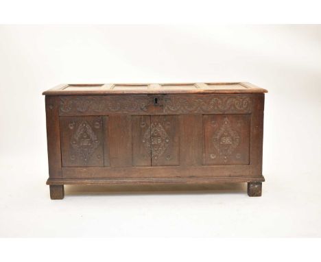 A carved and dated 18th century oak coffer, the moulded four-panel top above a guilloche carved frieze, the front with three 