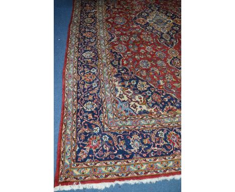 A LARGE PATTERNED WOOLLEN CARPET SQUARE, on red and blue ground, approximate size 369cm x 242cm