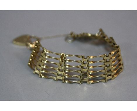A LATE 20TH CENTURY 9CT GOLD SIX BAR STRAIGHT GATE BRACELET, fitted to a padlock and safety chain, measuring approximately 18