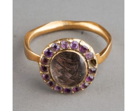 A 19th century yellow metal oval mourning ring, centred with a plait of hair under glazed, within a border of purple paste st