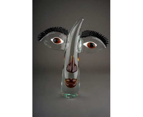 A Murano style clear and coloured glass stylised face, the clear horn shaped face with wing shaped sides with black eyelashes