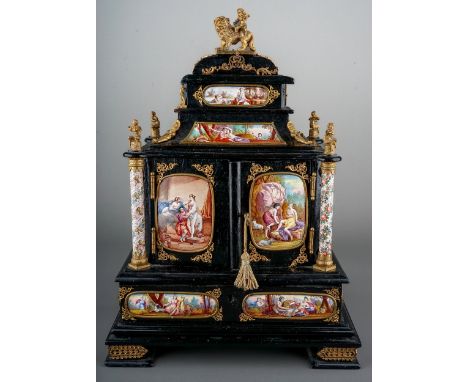 Antique Viennese ebonised wooden table cabinet, decorated with enamelled panels.  Gilt metal mounts.  37cm tall, 26cm wide.  