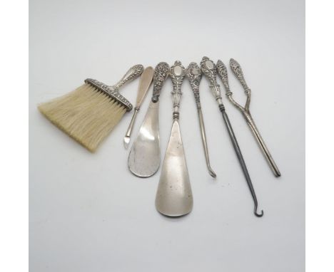 A silver handled shoe horn, another example, a silver handled brush, a silver handled button hook, and another, a pair of sil