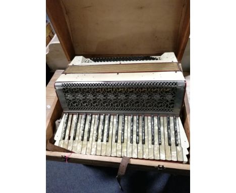 Italian pearloid accordion, pierced white metal grill with foliate design, bellows 47cm wide, some losses; in a wooden case.