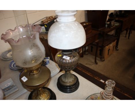 A glass and brass oil lamp with drop in font and milk glass shade