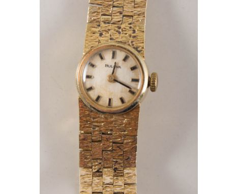 Lady's Bulova wrsist watch, circular cream baton dial in a 20 micron gold-plated casew ith integral bark textured brick desig
